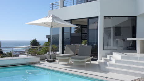 relaxing by poolside, two lounge chairs under umbrella at modern luxury home, copy space