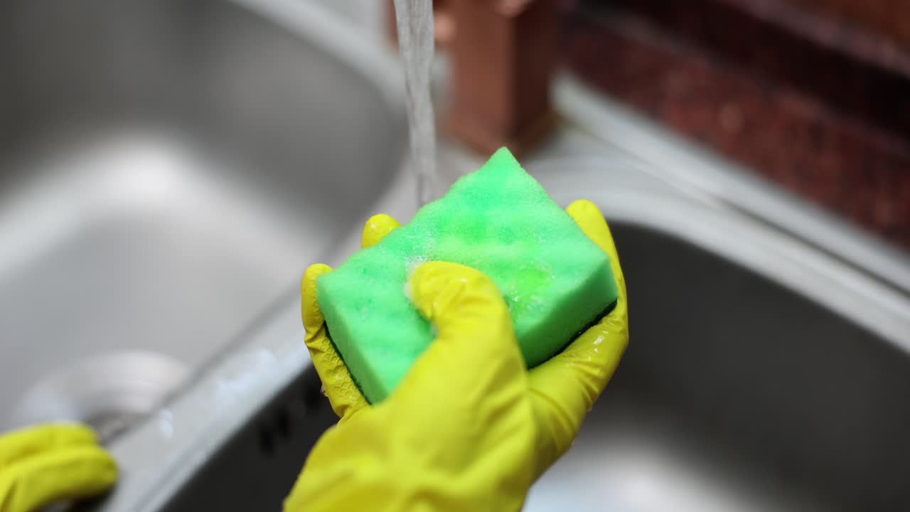 Washing a sink with a sponge and rubber gloves