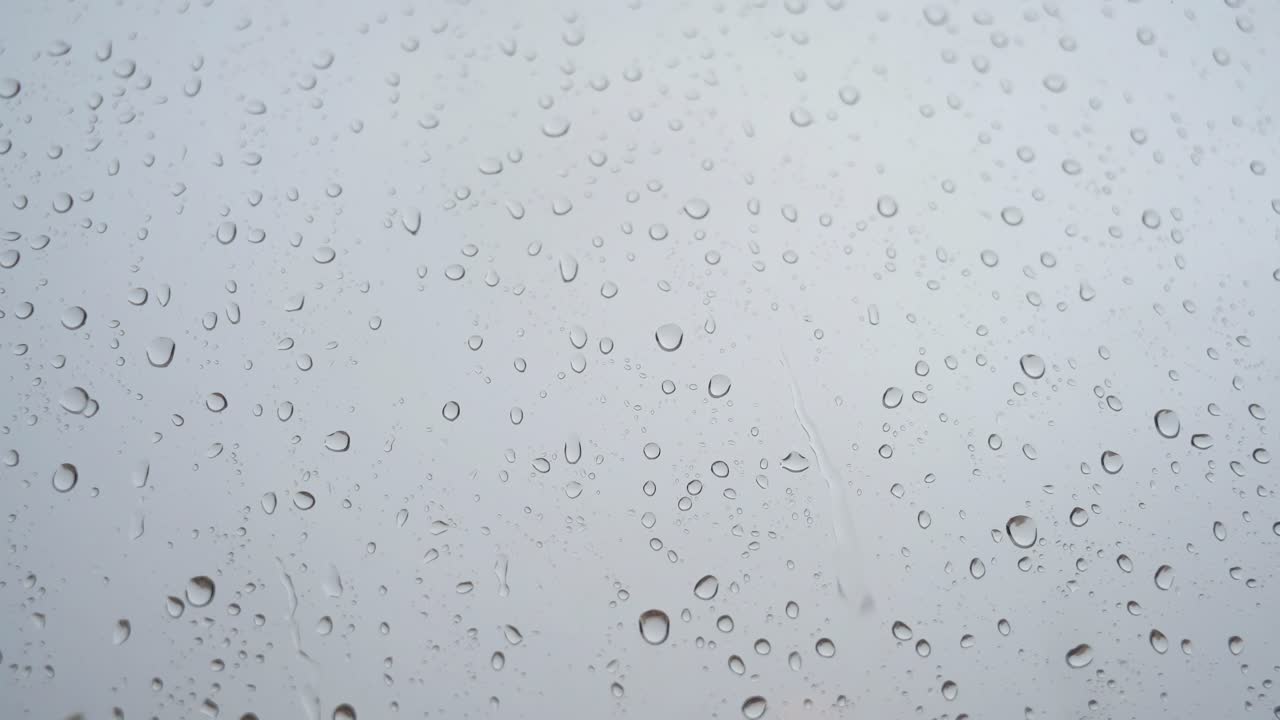 un metraje en cámara lenta de una vista estrecha de las fuertes gotas de lluvia vistas a través de un vidrio de ventana