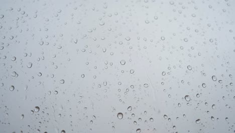 un metraje en cámara lenta de una vista estrecha de las fuertes gotas de lluvia vistas a través de un vidrio de ventana