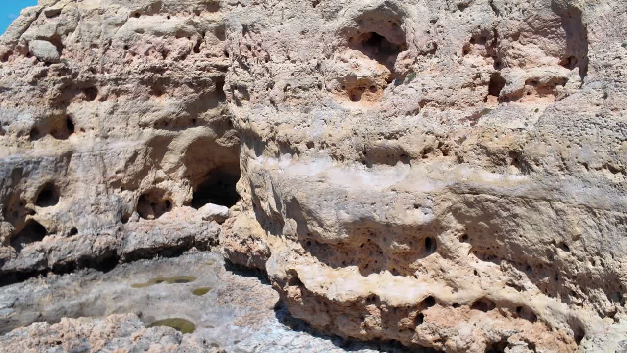Close up of a weathered sandstone cliff face showing various cavities and small caves, highlighting the effects of erosion in Algar Seco, Carvoeiro