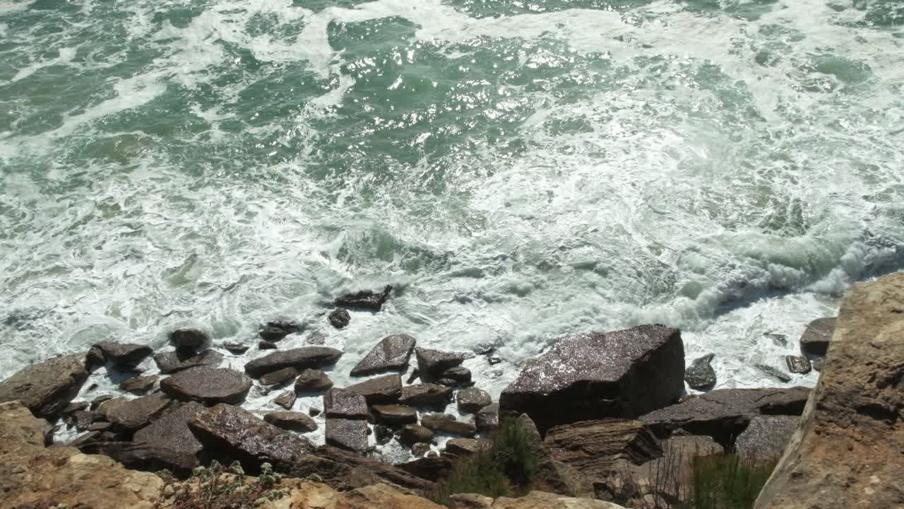 Come schiuma bianca, l'acqua dell'oceano si infrange sulla costa rocciosa.