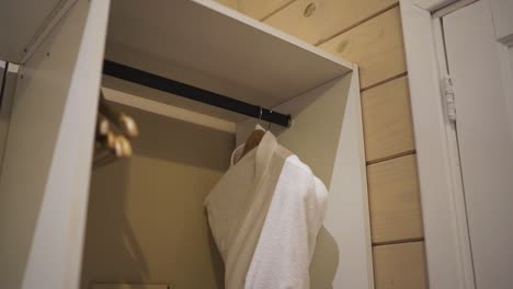 a slow panning shot reveals a robe closet in a hotel room, featuring a neatly hanging white bathrobe, inviting guests to relax and enjoy their stay in comfort and luxury