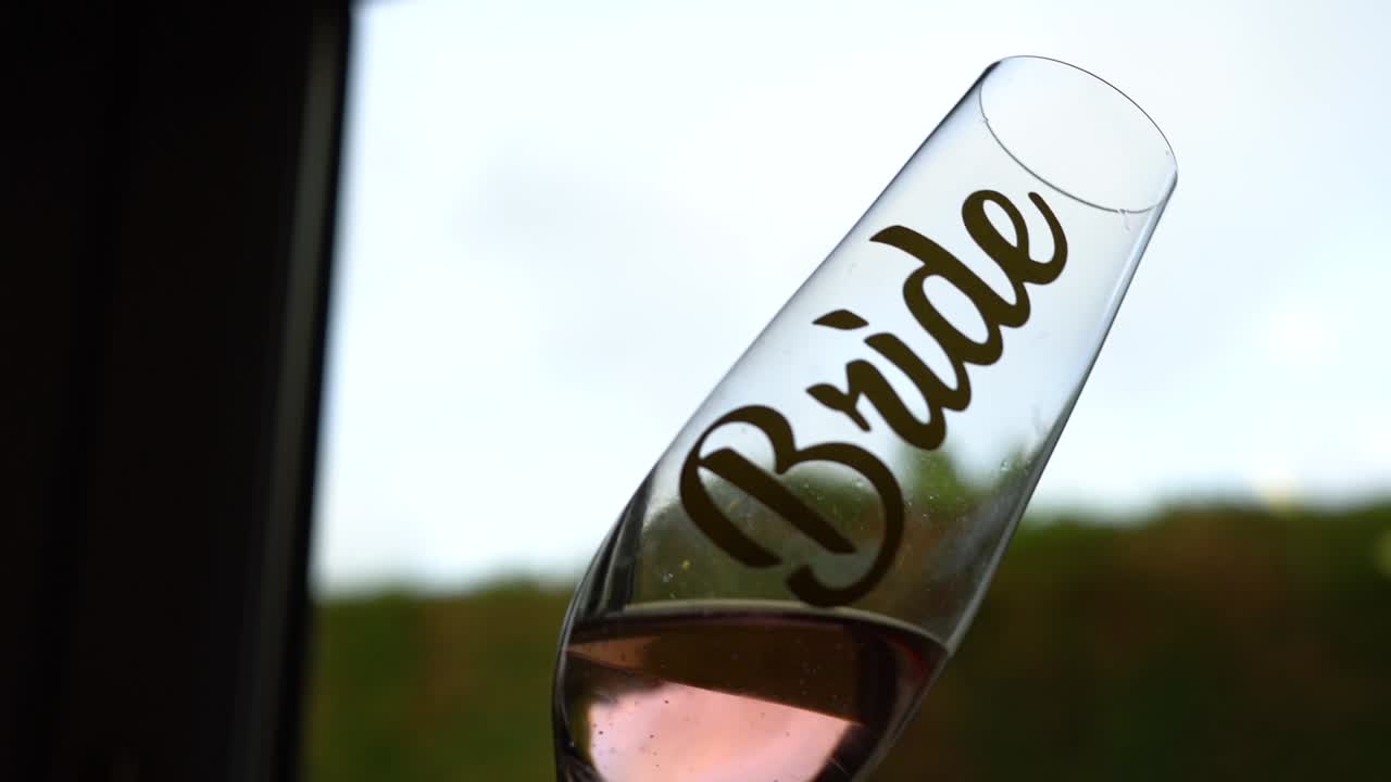 Ett bröllopsglas fyllt med rosévin som virvlar i slow motion mot ett ljust fönster.