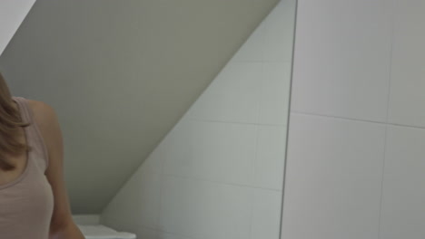mujer joven limpia el espejo del baño