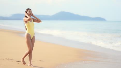 Una-Mujer-Joven-Y-Bonita-Camina-Por-Una-Playa-De-Arena-Dorada-Mientras-Llega-El-Oleaje