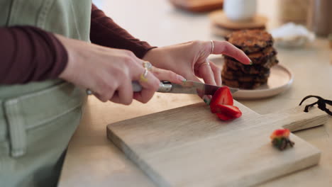 hands, knife and cutting strawberry in kitchen