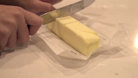 Ein-Mädchen-Schneidet-Butter-In-Kleinere-Stücke,-Um-Sie-Zum-Backen-Von-Butterkeksen-Für-Millionäre-Zu-Schmelzen