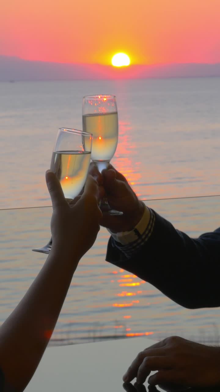 Coppia che brinda con calici di champagne al tramonto sul mare