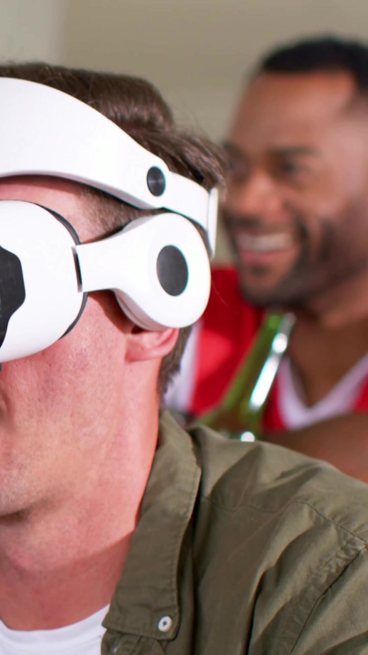 Vertical video: Wearing white headset, man in olive shirt turning, using pad at home, playing VR