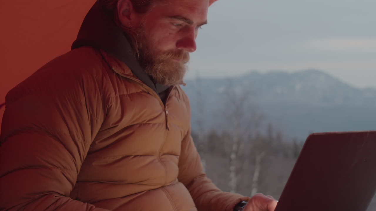 Tourist Using Laptop in Tent during Winter Camping
