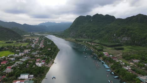 el dron sigue el río con un pequeño pueblo a ambos lados