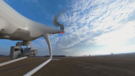 close-up side view of dji phantom 4 quadcopter drone flying backwards over fields