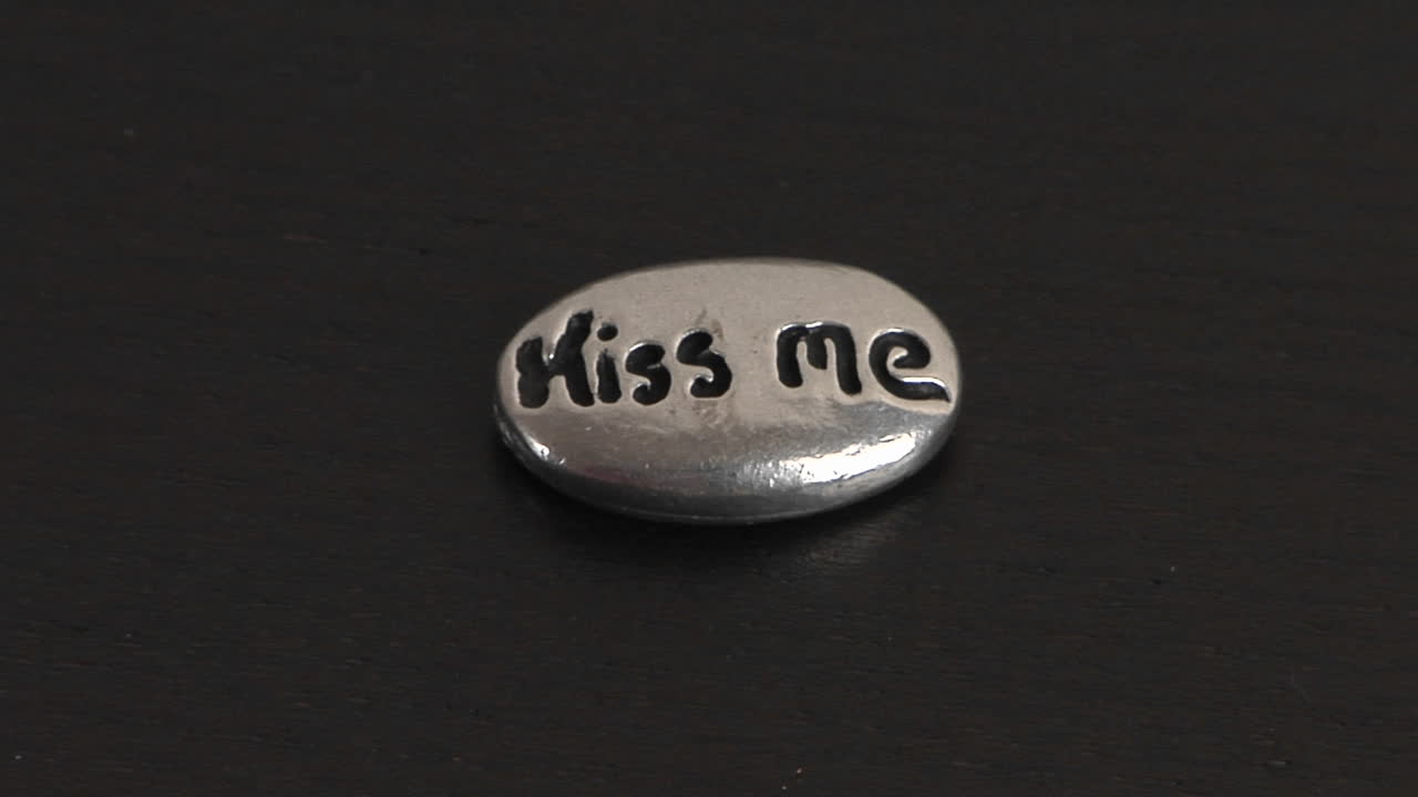 The words kiss me are carved into a small smooth ovalshaped stone