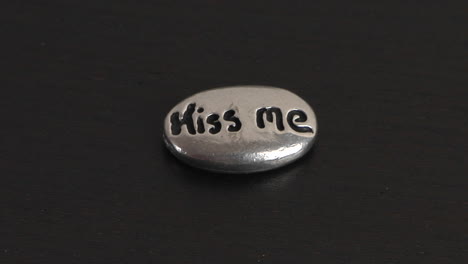 the words kiss me are carved into a small smooth ovalshaped stone