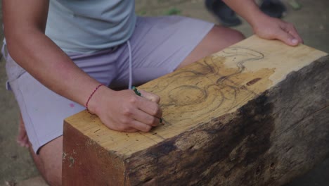 indonesian wood carver create a pattern design of the balinese mythological creature, barong, on block wood before starting to carve the wooden mask, barong bangkung