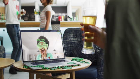 smiling african american woman wearing clover shape items on video call on laptop