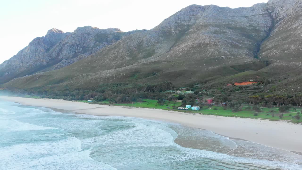 дронные кадры горных холмов, встречающихся с океаном на пляже рано утром