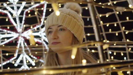 Mujer-Caminando-En-Una-Calle-Decorada-Con-Luces-En-La-Noche-Durante-La-Navidad