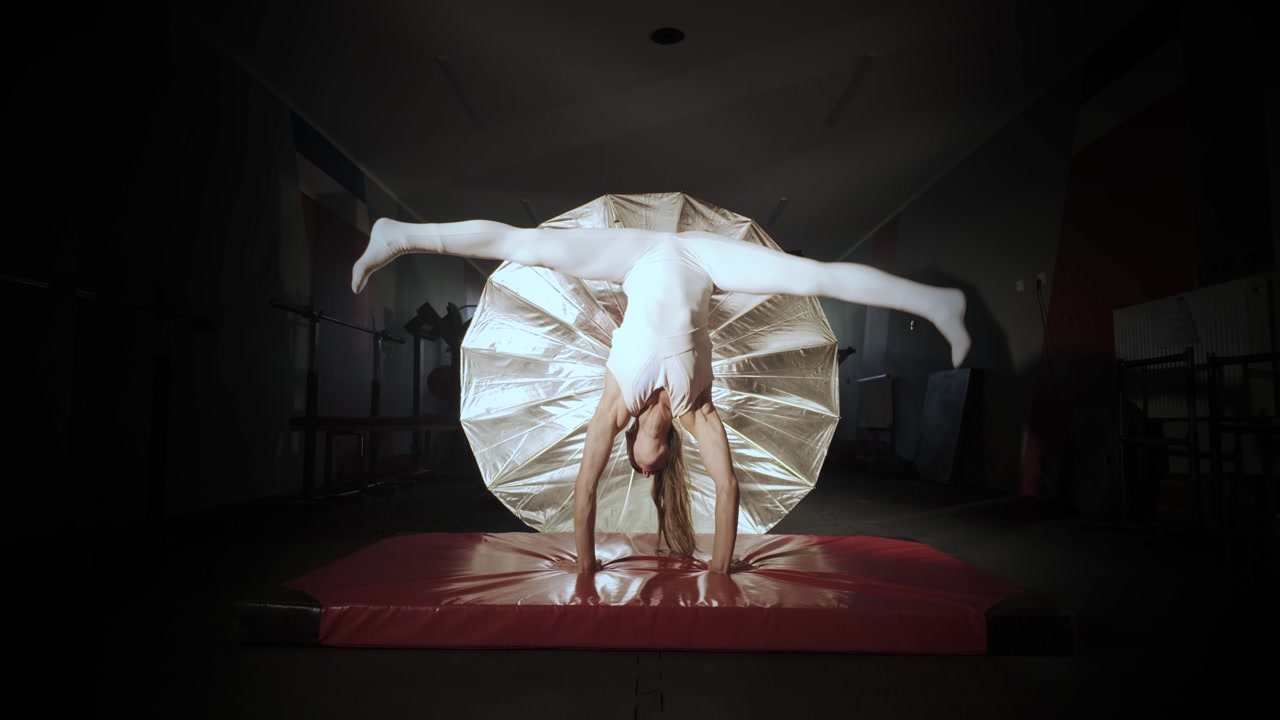 Female gymnast in a tight white leotard falling while attempting a trick