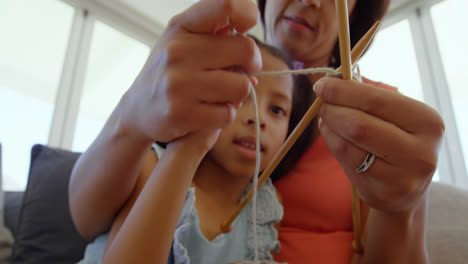 Low-angle-view-of-black-mother-teaching-her-daughter-knitting-in-a-comfortable-home-4k