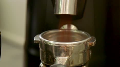 how to make a real italian espresso: footage of barista grounding coffee into filter