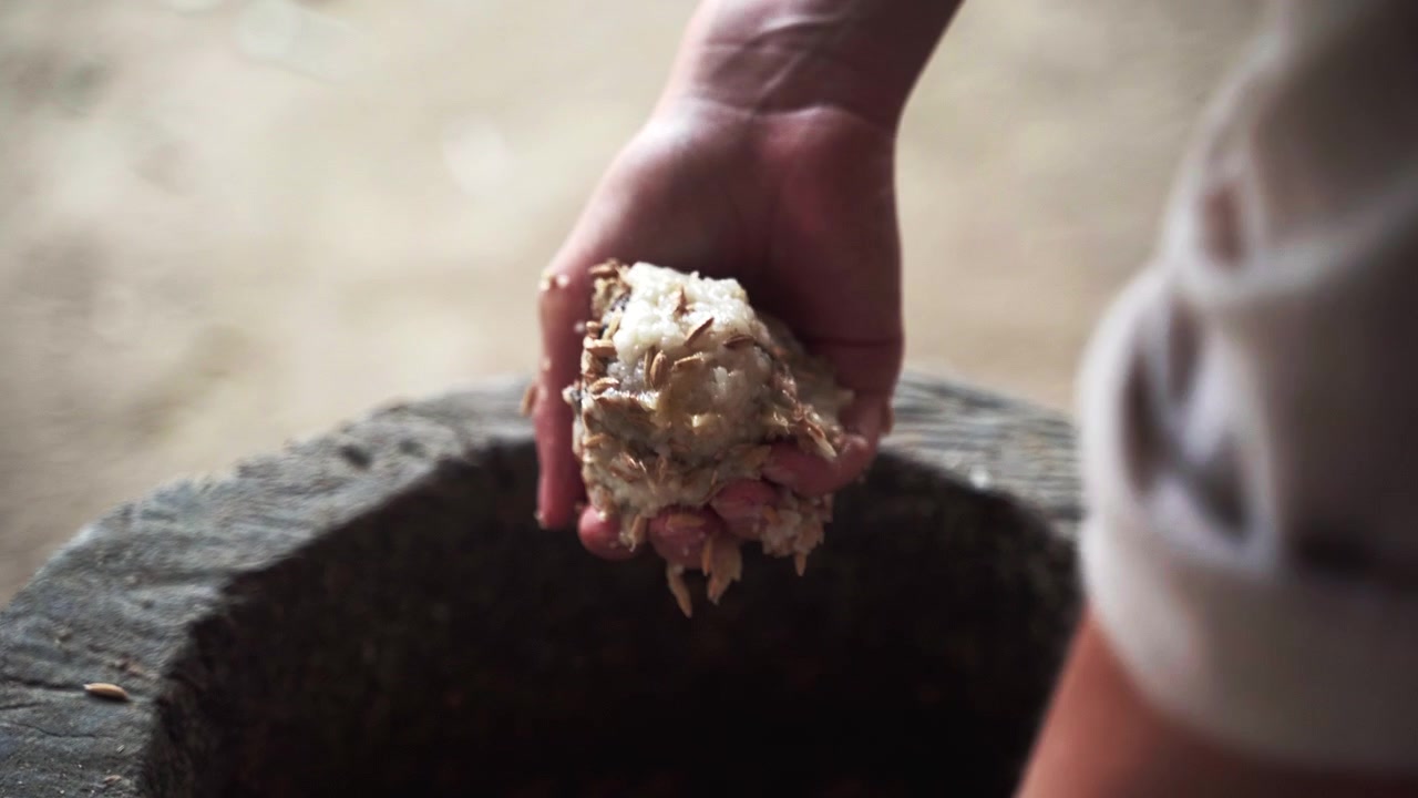 Preparazione manuale di cibo a base di palline di riso per elefanti in un secchio di legno.