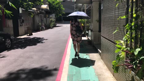 a woman walking outside taipei city on a hot summer day with an umbrella