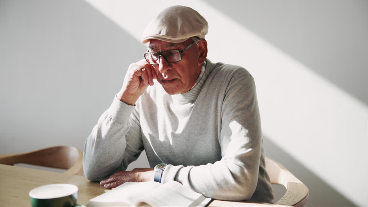 Senior man reading a book at the table