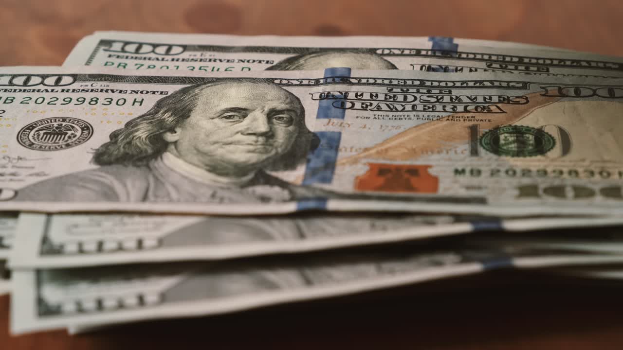 cien dólares está aumentando uno por uno billete contra la mesa de madera.