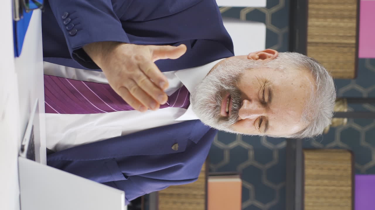 노인 사업가의 수직 비디오는 노트북에서 자신의 실패를 슬프게 보고 있습니다.