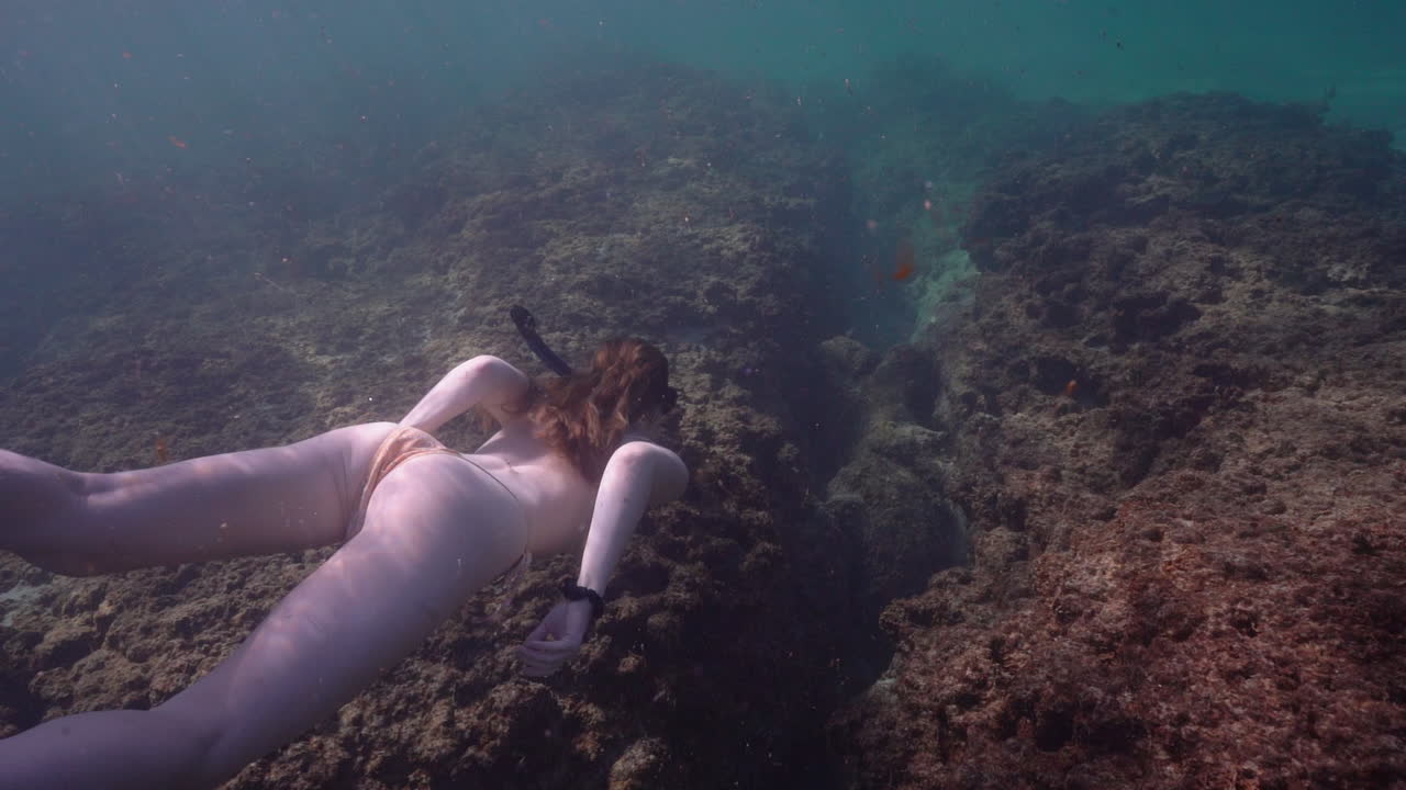 una mujer joven nada sobre un arrecife en la playa de bonim, israel