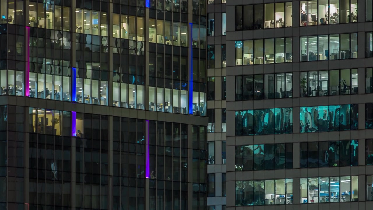 Vista de perto das janelas panorâmicas de escritórios nos arranha-céus do International Business Center da Cidade à noite, timelapse do alto.