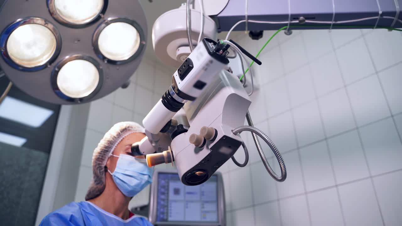 View of surgeon during operation. Doctor using microscope for work at operating room