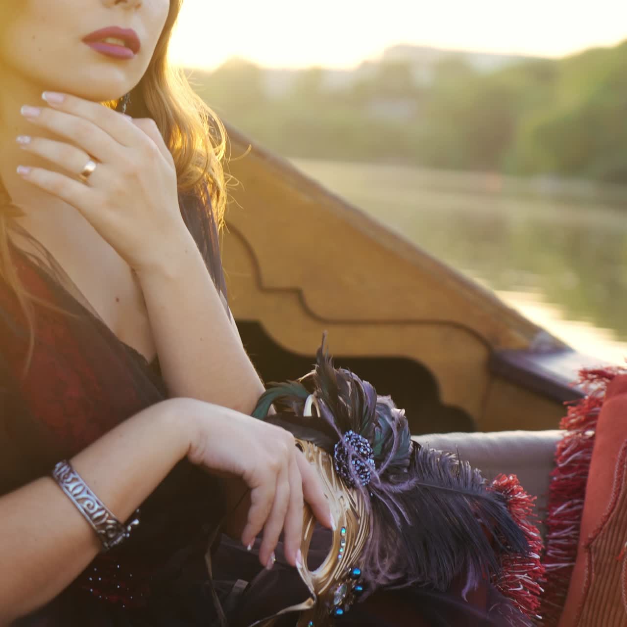 A mysterious woman in effect dress is looking thoughtfully at the river in the gondola at sunset. Close-up. Blurred Background
