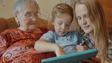 a família usa um tablet sentada no sofá.