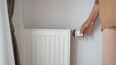 mujer ajustando el termostato del radiador