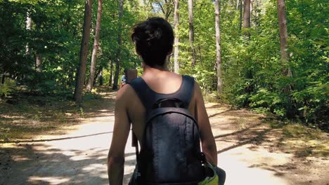 shot of pine tree leafs pans down to shirtless teenage climber boy backpacking