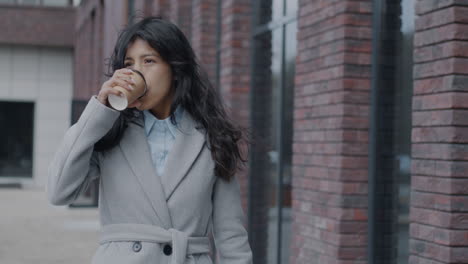businesswoman walking and drinking coffee