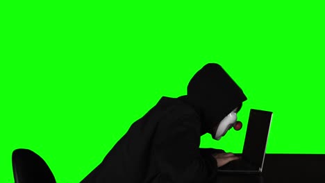 masked hacker doing cybercrime with laptop