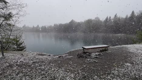 grandes copos de nieve están cayendo en el banco con vista sobre el lago místico