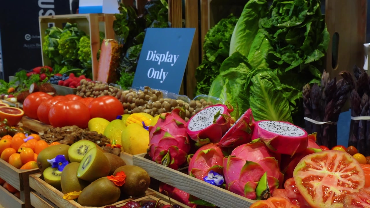 Chicago, USA, 27. maj 2026: Chicago fremviser dragefrugt, salat og tomater. Skårne tomater, kiwi, citrusfrugter og grøntsager er arrangeret i trækasser inde i en messehal.