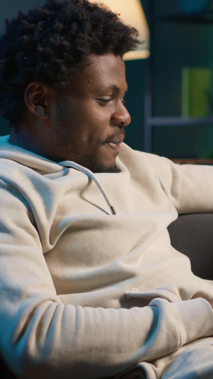 Glad afroamerikansk mann som drikker fra et krus i sofaen