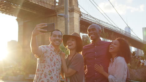 un grupo de amigos posando para una selfie frente al puente de brooklyn