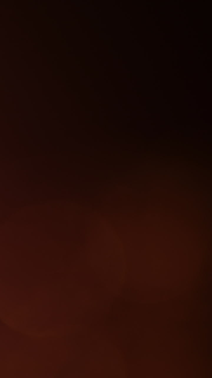 Fughe di luce bokeh arancione tenue che si muovono su uno schermo scuro.