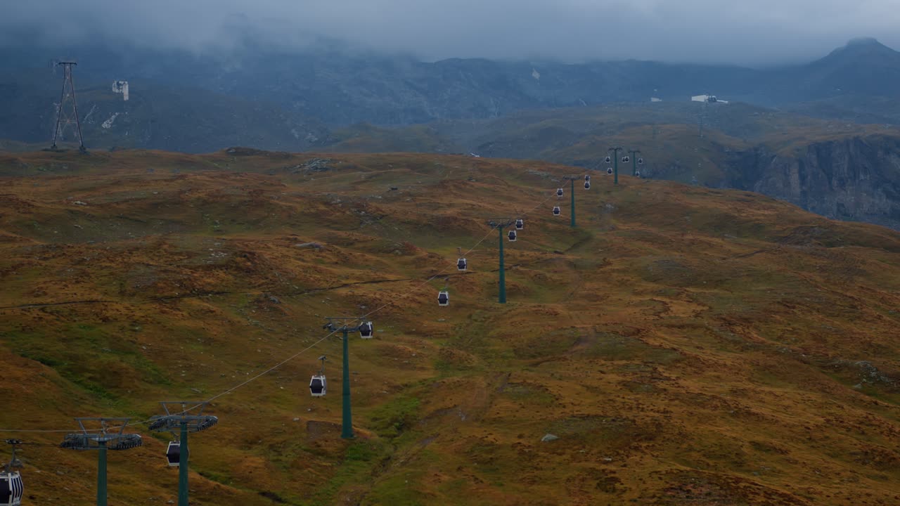 Svævebaner krydser efterårsklædte bakker i Cervinia, Alperne under en skyet himmel