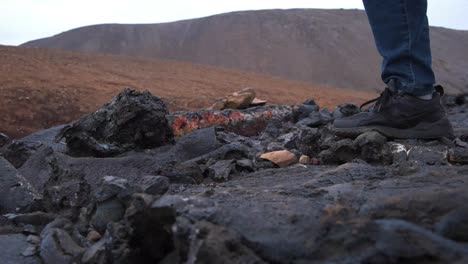 cerca de zapatos de excursionista caminando sobre rocas volcánicas afiladas en islandia