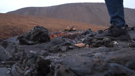 close up of hiker's shoes walking over sharp volcanic rocks in iceland