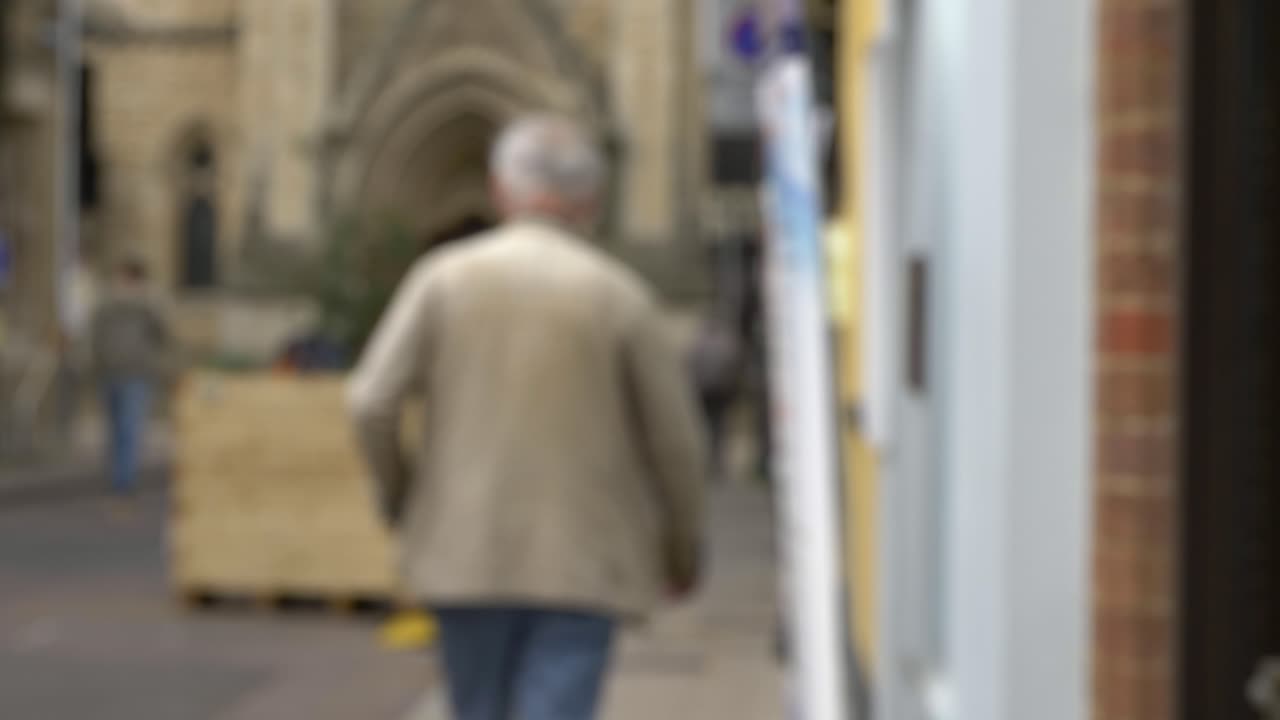 toma desenfocada de un anciano caminando por una calle tranquila en oxford