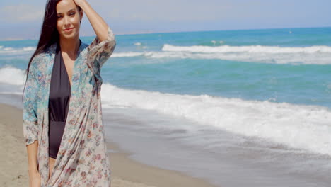 una mujer joven y bonita en verano se viste en la playa.
